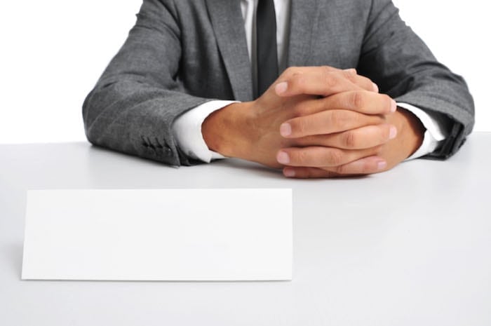 Man In Suit Sitting In A Desk With A Blank Signboard In Front Of