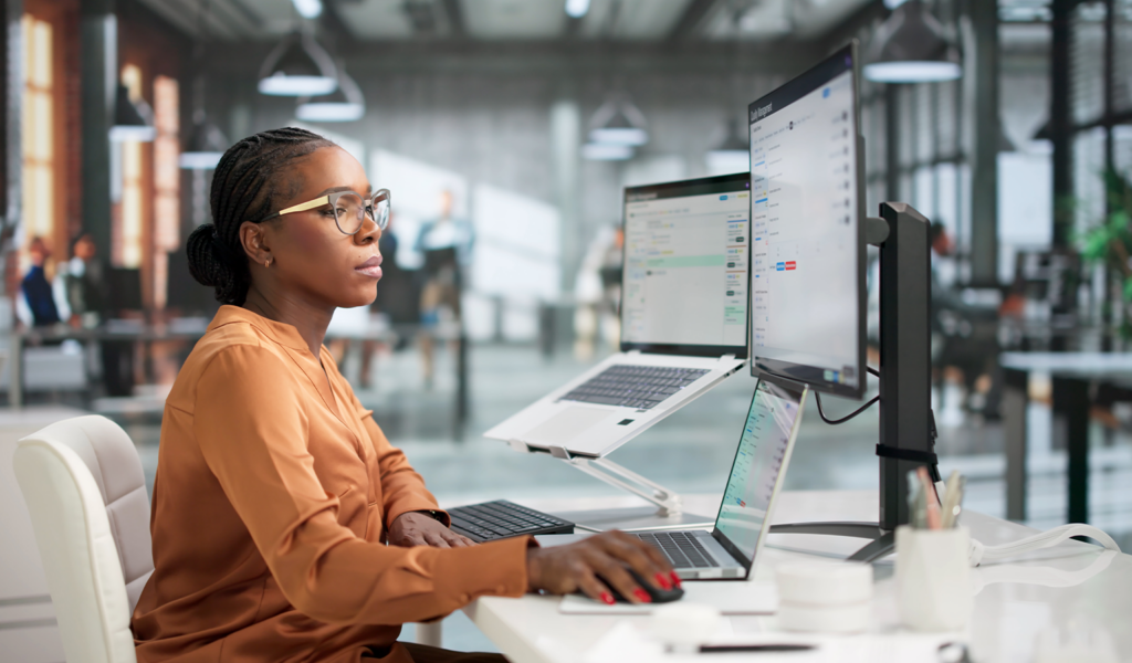 Woman working at dual monitors in an office, representing the compliance review process behind FINRA compliance content