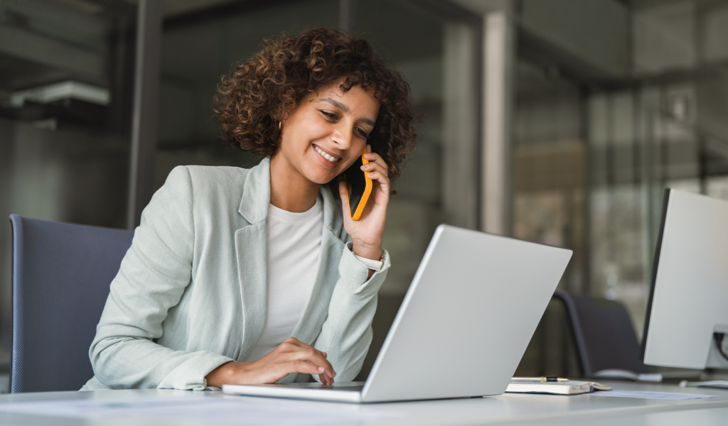 Sales rep on a phone call while looking up information in a sales portal on her laptop