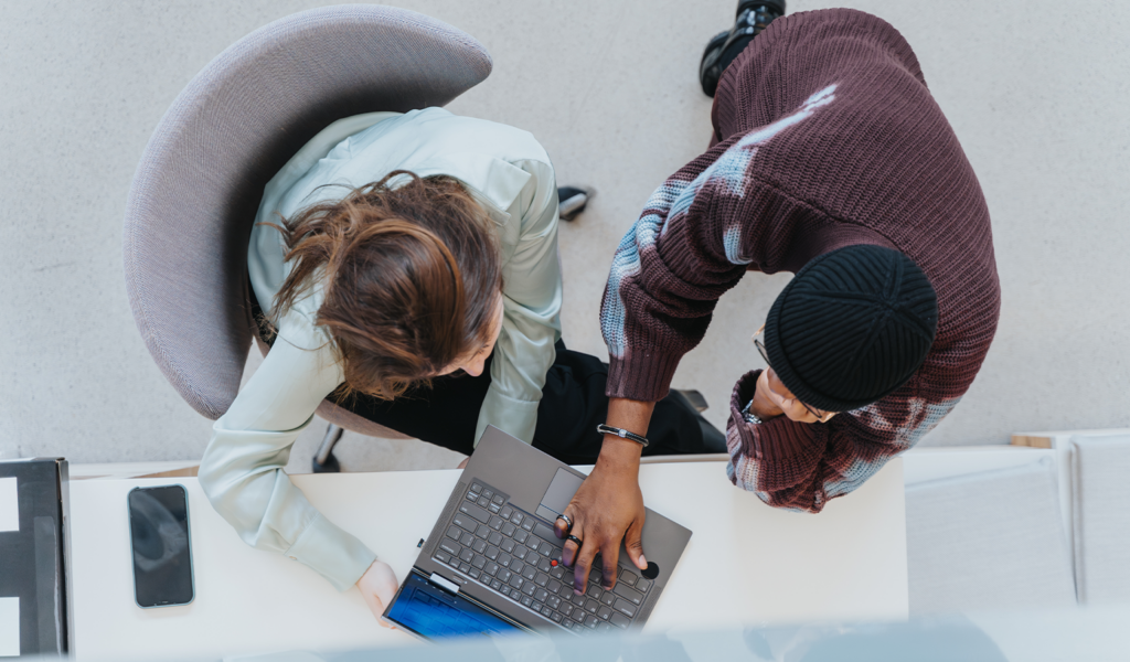 Overhead view of two colleagues collaborating on a laptop, reviewing sales enablement content together